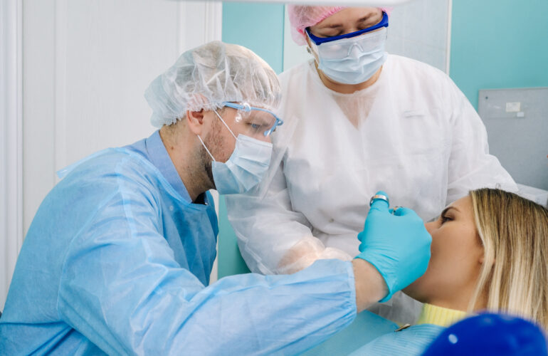 Dentists performing a gum graft procedure on a patient in a clinic.